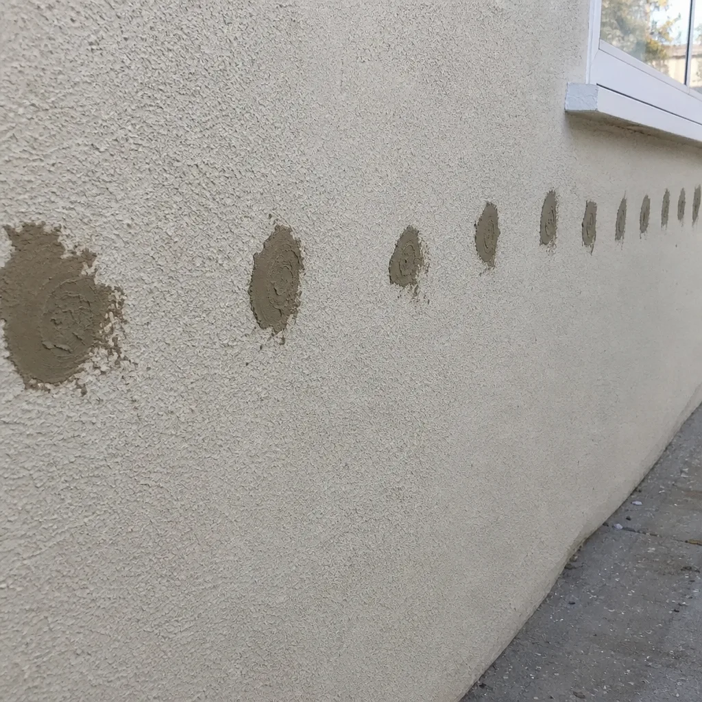 Professional contractor injecting wall insulation into exterior home siding in West Hollywood, CA